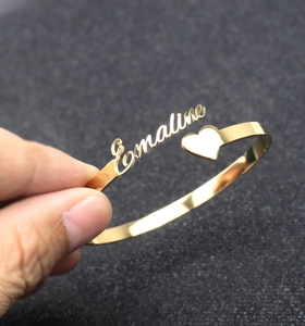 Detailed view of custom gold name bracelet featuring Emaline script and heart accent