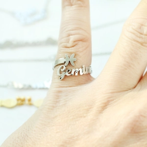 Detail of silver Gemini letter ring with butterfly accent on model finger
