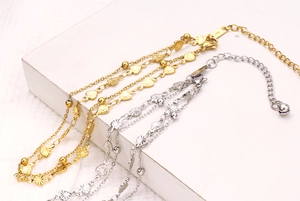 Close-up of dual-layer titanium steel anklets with 18k gold plating and heart charms