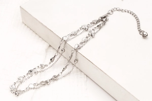 Detailed macro view of triple-layered silver anklet featuring heart charms and beads