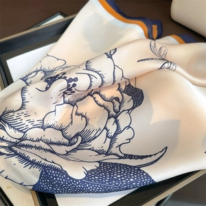 Close-up of silk scarf with floral and dragonfly prints and contrast stitching edges
