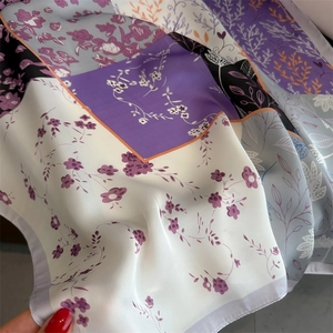 Détail d'un foulard en soie à imprimé fleuri avec bords violets et orange et texture