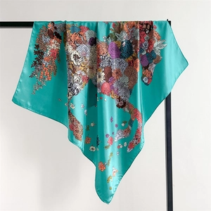 Close-up of a teal floral silk scarf draped on a display stand showing artistic patterns