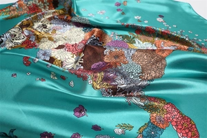 Detail of turquoise floral silk scarf showing vibrant flower prints and satin texture
