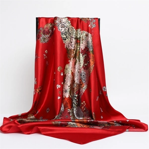 Close-up of a glossy red satin square scarf with vibrant floral horse prints and elegant drape