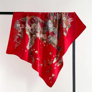Detail of vibrant floral print on red satin scarf with premium silk texture and glossy finish