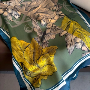 Détail d'un foulard en soie vintage avec fond vert foncé et motifs floraux jaunes
