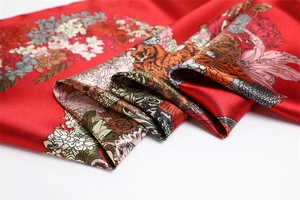 Close-up of red floral silk scarf with vibrant horse and flower prints and silky texture