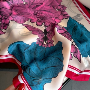 Vue détaillée d'un foulard en soie à fleurs montrant la texture satinée et le bord rayé