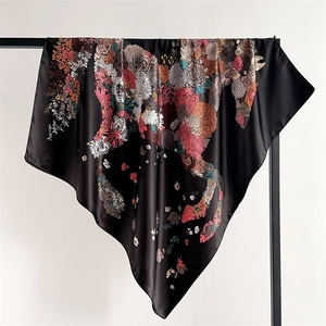 Close-up of a floral horse print silk scarf with satin finish draped on a black stand