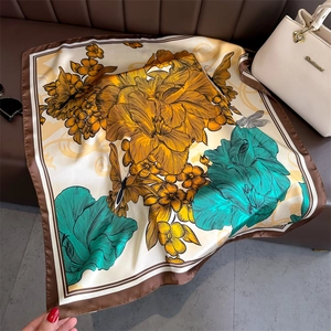 Détail d'un carré de soie vintage aux motifs floraux et papillons sur surface cuir