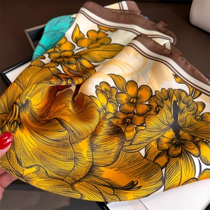 Gros plan du foulard en soie vintage avec fleurs jaunes et oranges et bordure marron