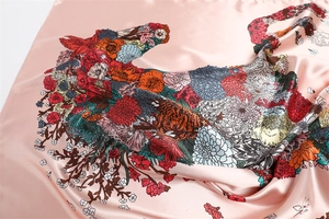 Detail of pink silk scarf showing vibrant floral and tiger head patterns with satin sheen