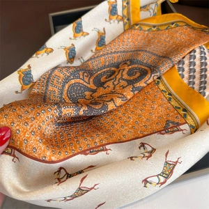 Elegant silk scarf featuring horse print and geometric patterns in orange and beige tones