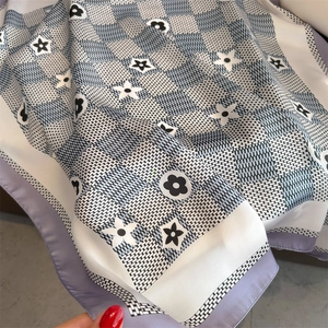 Detailed view of silk-like floral square scarf with blue and black checkered patterns