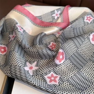 Detailed close-up of silk-textured square scarf with pink floral and geometric patterns