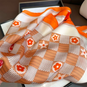 Elegant orange and white checkered silk scarf with floral patterns and glossy texture