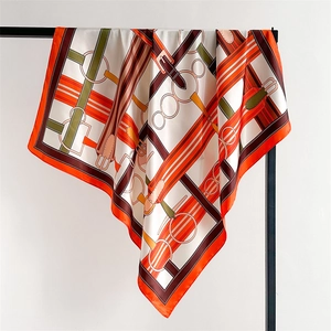 Macro detail of silk-like scarf featuring equestrian belts and stirrup patterns in orange