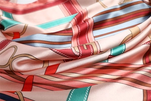 Close-up of silky satin scarf with pink base and elegant chain print pattern