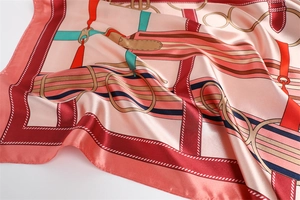 Detail of equestrian print silk scarf with bridle motifs on soft pink background