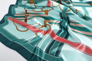 Detailed macro view of mint green silk scarf with equestrian horse buckle and strap prints