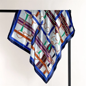 Detailed view of silk square scarf featuring royal blue borders and equestrian belt motifs