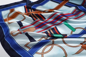 Macro detail of silk-like satin scarf featuring nautical chain and horse bit patterns