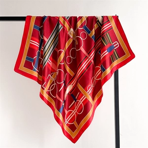 Detail of red silk-feel scarf featuring classic gold horse harness and belt buckle patterns