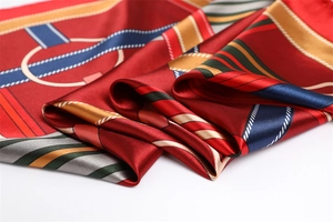 Detailed view of red silk scarf with geometric ring patterns and shiny smooth texture