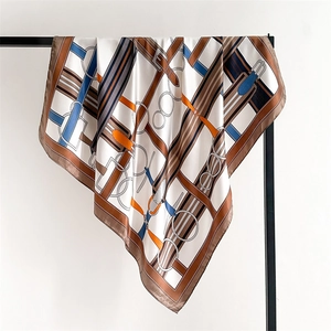 Detailed close-up of ivory silk scarf with equestrian belt and metal buckle patterns