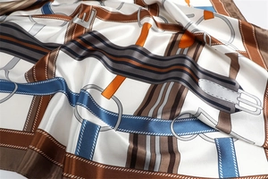 Macro view of silky satin scarf featuring luxury equestrian prints and horsebit details