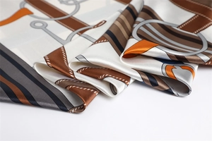 Detailed view of the luxury satin scarf featuring equestrian horsebit patterns and silk texture
