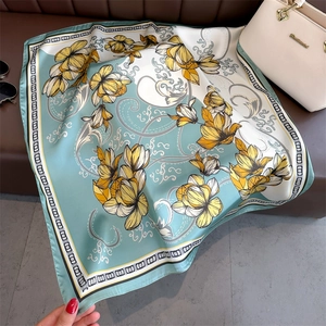 Détail d'un foulard en soie vert menthe montrant la texture et le motif floral élégant