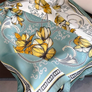 Gros plan d'un foulard en soie vert clair avec magnolia jaune et motifs de nuages