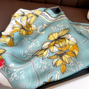 Détail d'un foulard floral soyeux en vert menthe et jaune montrant un éclat satiné