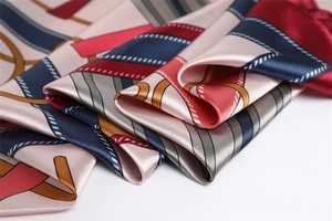 Macro detail of silky satin scarf featuring vintage equestrian print and gold chain motifs