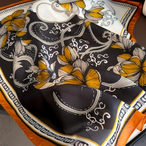 Détail d'un foulard en soie à imprimé floral avec bordures orange et motifs paisley