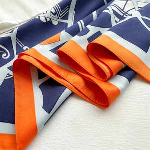 Close-up of geometric pattern silk scarf showing navy, white, and orange twill fabric