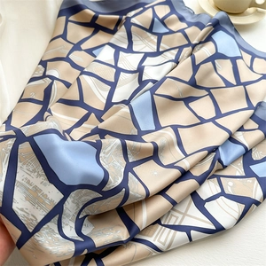 Close-up of geometric silk scarf with blue and beige blocks and fine line patterns