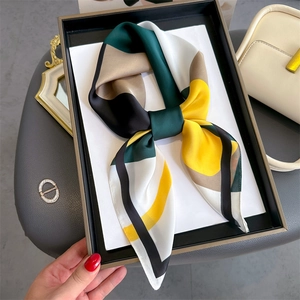 Geometric color-block silk scarf in deep green and yellow, styled on a minimalist tray