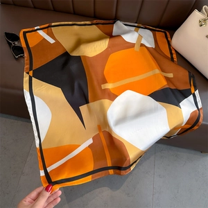 Detail of colorful geometric pattern silk square scarf on a leather sofa