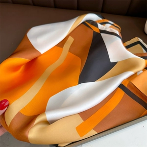Detail of silk-like square scarf featuring geometric color blocks and satin finish
