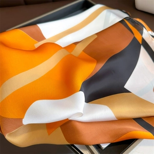 Macro detail of geometric print silk scarf showing glossy texture and vibrant colors
