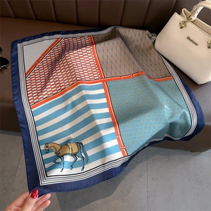 Detail of color-block horse print silk scarf with geometric patterns on leather sofa