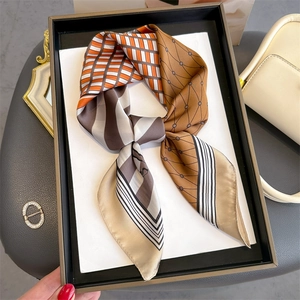 Detail of multi-patterned silk scarf tied in a bow with orange and brown geometric prints