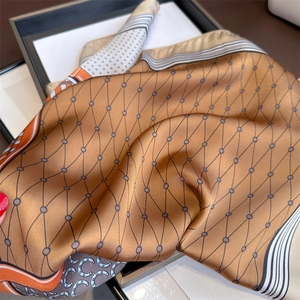 Detailed close-up of horse motif silk scarf with golden brown tones and satin texture