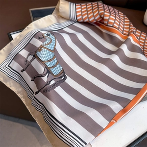 Detailed view of lightweight silk scarf featuring equestrian horse prints and orange borders