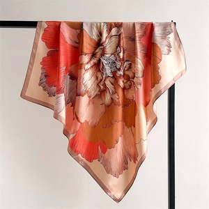 Detailed texture of silk-like satin scarf featuring floral patterns and warm orange tones