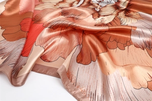 Close-up of elegant floral print silk square scarf with warm gradient tones and satin sheen