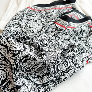 Detail of silk scarf featuring baroque floral patterns and red Greek key borders